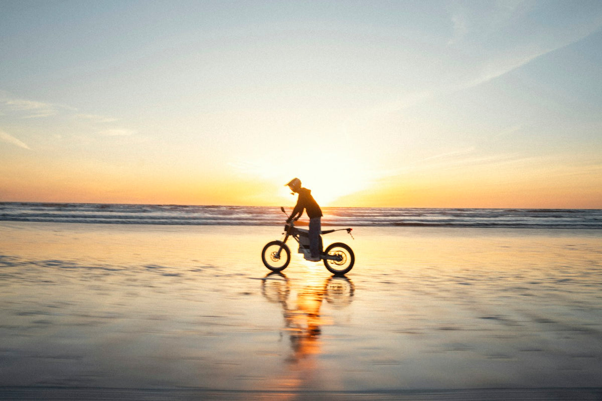 E-Bike-Fahrer am Strand bei Sonnenuntergang