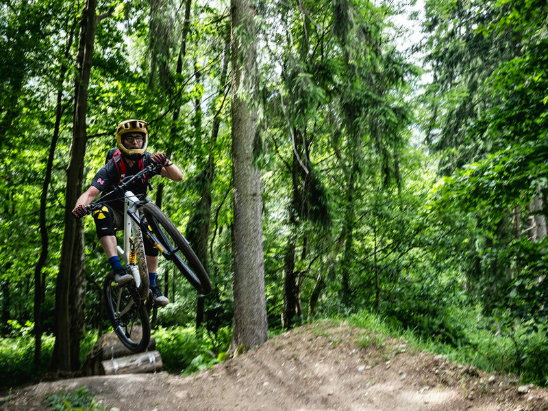 Mountainbiker macht einen Trick im Wald